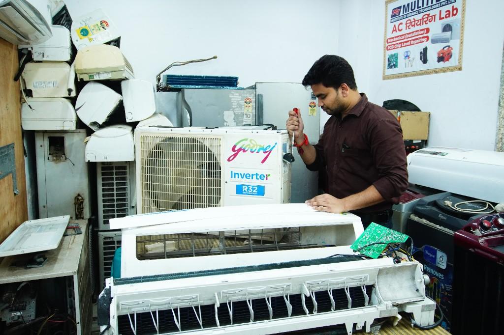 A technician repairing an air conditioner in a local service workshop