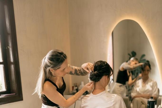 A stylist arranging a client's hair in a salon chair