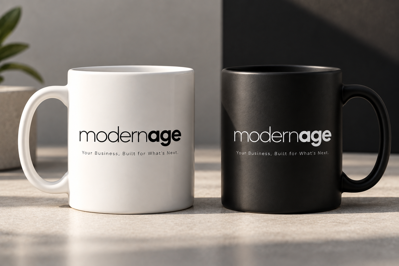 White and black mugs printed with the Modern Age wordmark, in studio light